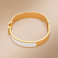 Gold hinged bangle with white enamel inlay