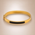 Gold hinged bangle, black enamel stripe
