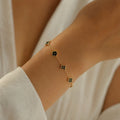 Gold chain bracelet, black enamel flower & star stations