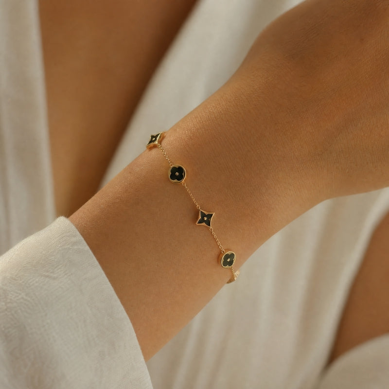 Gold chain bracelet, black enamel flower & star stations