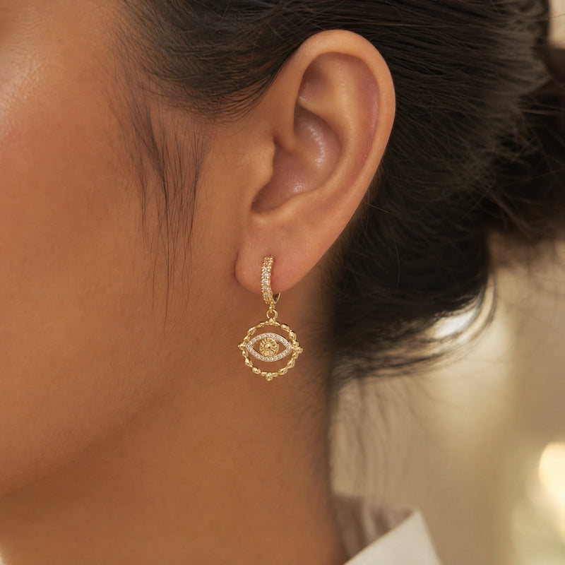 Gold huggie drops, CZ evil-eye charm, scalloped frame
